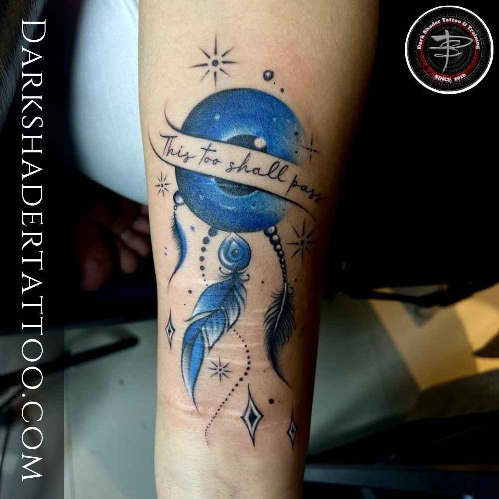 A symbolic tattoo on a girl’s wrist featuring a blue circle, feather, stars, and intricate design.