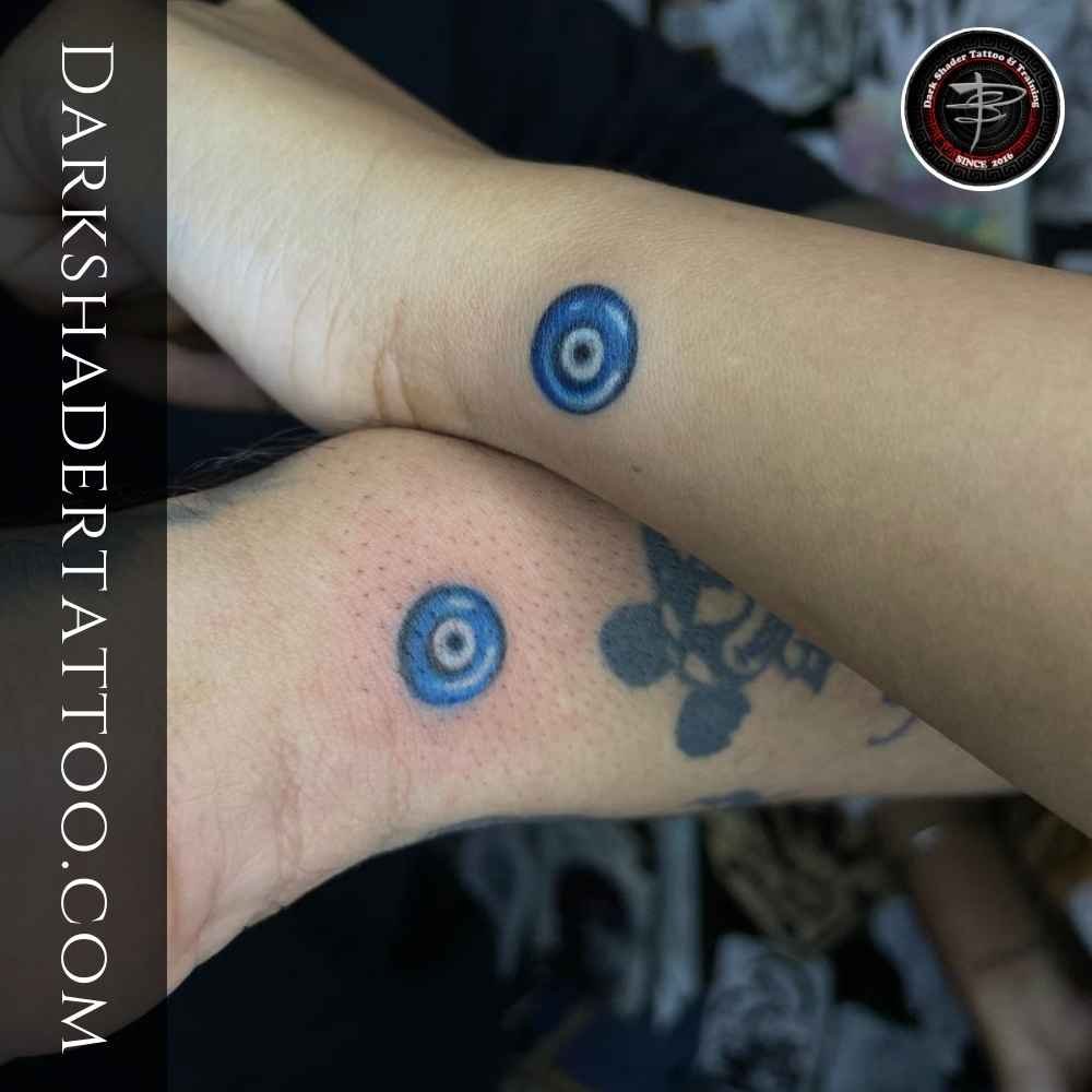 A minimalistic blue dot tattoo on the hands of a man and woman, symbolizing a relationship and security.