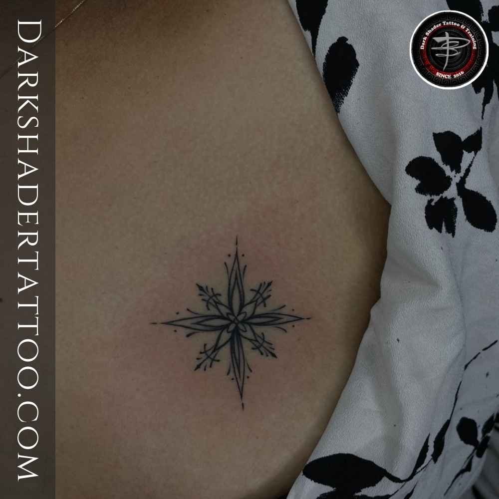 A minimalistic star tattoo on a girl’s left chest, showcasing a simple and elegant tattoo design.
