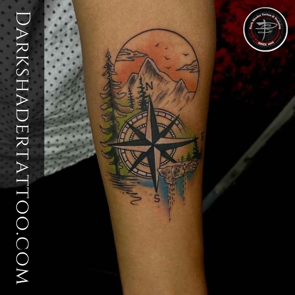 A colorful tattoo of a beautiful scenery featuring stars, mountains, sun, trees, and a lake, designed in a creative style.