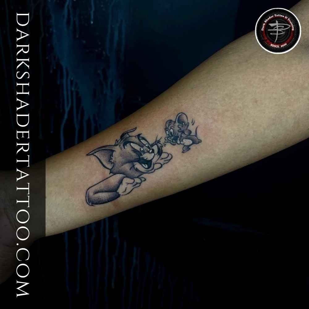 A fun Tom and Jerry tattoo on a girl’s hand, featuring the iconic cartoon characters in a beautiful design.