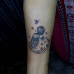 A beautiful tattoo design showing a girl's head on a boy's shoulder with colorful butterflies and love symbols, located on the hand. Perfect for lovers.