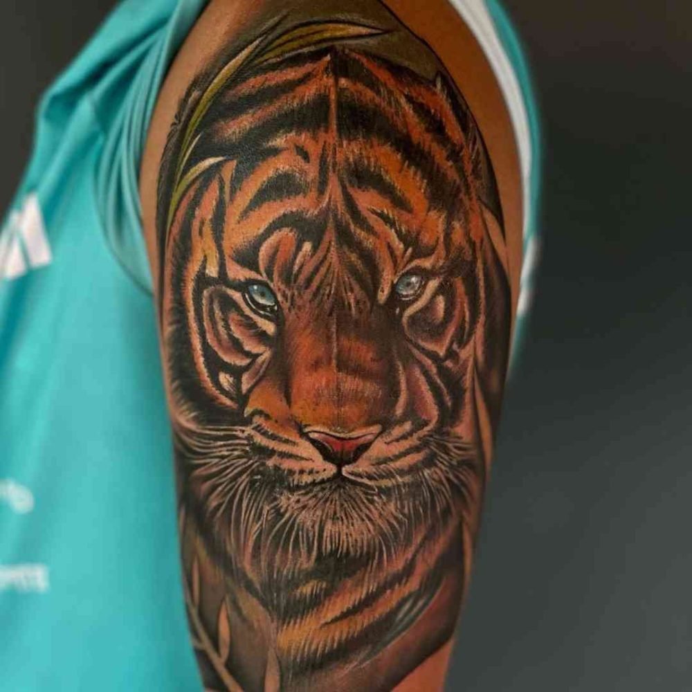 A fearful tiger face tattoo with yellow color designed on the shoulder, showcasing bold details and powerful expression, created at Dark Shader Tattoo studio in Kolkata.